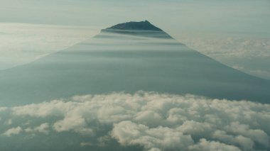 Bulutlar denizini delip geçen bir dağın dingin güzelliğini yakala. Bu görüntü huzuru ve merakı çağrıştırıyor, seyahat, doğa ve ilham verici temalar için mükemmel. Özgeçmiş ve reklamlar için ideal.