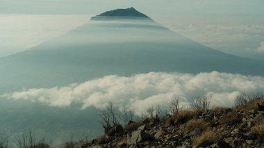 Bulut denizinin üzerinde çarpıcı bir dağ yükseliyor. Dramatik manzara, seyahat, doğa ve macera temaları için mükemmel. Huzuru, huzuru ve manzaranın güzelliğini çağrıştırıyor.