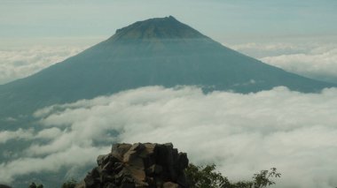 Bulutlarla çevrili çarpıcı dağ zirvesi. Sakin, huzurlu ve görkemli doğa manzarası. Macera, seyahat ya da manzaralı arka planlar için mükemmel. İlham verici bir manzara. Arkaplan olarak kullan