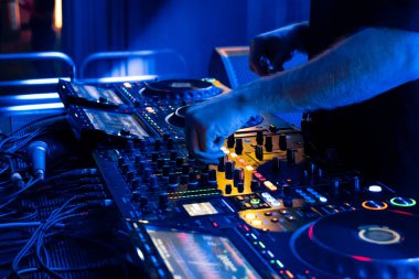 Profesyonel DJ, canlı gece kulübü atmosferinde gelişmiş ses panosunda şarkıları ustalıkla karıştırıyor.
