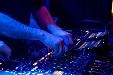 DJ, canlı bir kulüpte canlı bir mikserin ses seviyesini ayarlıyor.