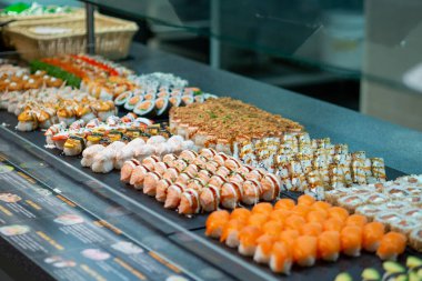 Restoran tezgahında zarif bir şekilde sergilenen çeşitli suşi dürümleri canlı renkler ve aşçılık sanatları sergiliyor.