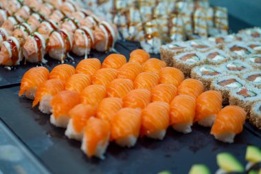 Siyah tabakta çeşit çeşit suşi, restoran menüsü ya da yemek blogu için mükemmel, taze somon suşi ruloları ve nigiri sergileniyor.