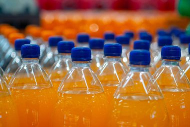 Portakal suyuyla dolu saf plastik şişeler üretim hattında.