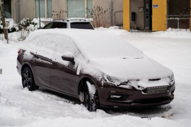 Kar kaplı bir araba kış caddesinde park edilmiş.