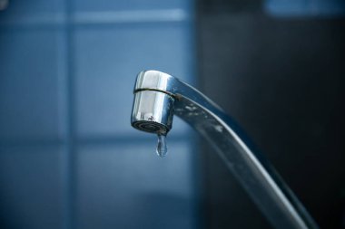 Sızdıran su damlatan musluğun yakın plan çekimi. Ev sorunlarını ya da su tesisatı kavramlarını göstermek için mükemmel.