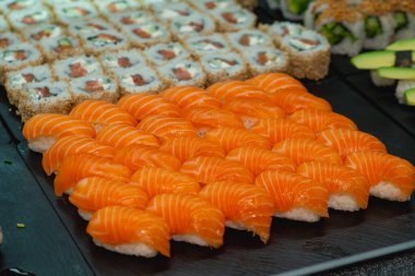 Taze somon suşisi ruloları ve siyah tabakta maki, restoran ya da yemek blogu için mükemmel.