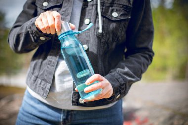 Yeniden kullanılabilir mavi bir su şişesiyle susuz kalan bir kadın.