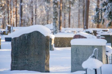 Huzurlu bir mezarlıktaki mezar taşlarının karla örtüldüğü sakin kış manzarası