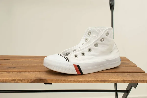 Ahşap arka planda kırmızı çizgili beyaz spor ayakkabılar..