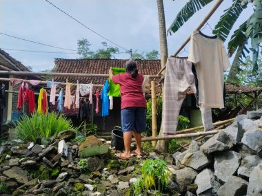 Kırsal alanda çamaşır ipine asılan bir kadının arka görüntüsü.