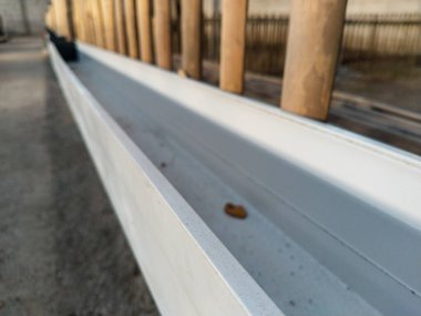 Ördek çiftliğinin içinde bambu kafesleri boyunca yerleştirilmiş plastik beslenme yalağı basit ve düzenli bir kümes hayvanı besleme sistemini gösteriyor.