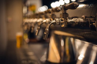 Modern bira fabrikasında bira fıçıları, yan görüş. Arka planda karanlık bir bar.