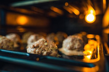 Köfteler için fırının tepsisine bak. Biraz ışık, sadece fırından gelen ışık. Sığ alan derinliği, bulanık arkaplan.