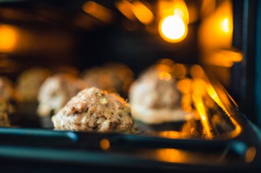 Köfteler için fırının tepsisine bak. Biraz ışık, sadece fırından gelen ışık. Sığ alan derinliği, bulanık arkaplan.