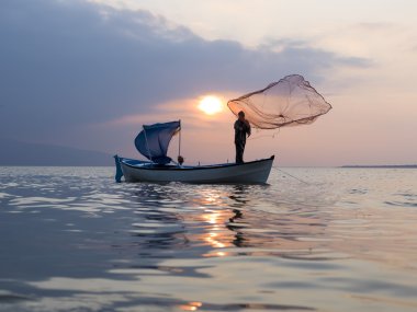 fisherman throught net to lake on sunset time clipart