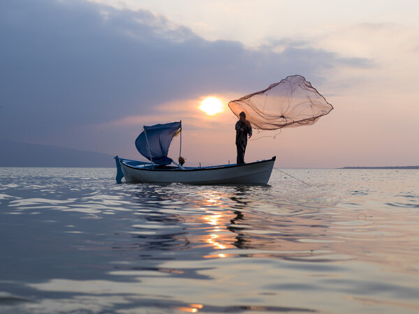 fisherman throught net to lake on sunset time
