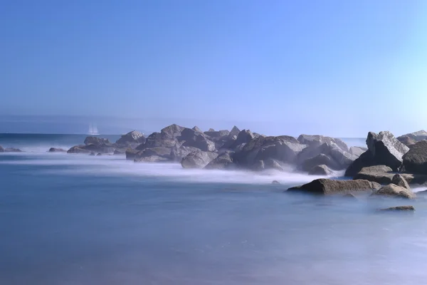 Tiro de larga exposición en la playa con hermosas rocas y el mar — Foto de Stock