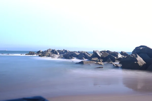 Lange blootstelling geschoten op het strand met mooie stenen en zee — Stockfoto