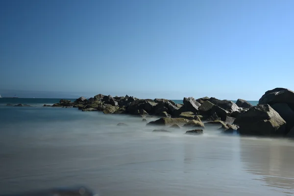 Tiro de larga exposición en la playa con hermosas rocas y el mar —  Fotos de Stock