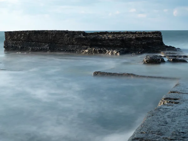 Tiro de exposição longa em rochas com ondas do mar — Fotografia de Stock