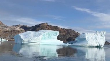 Grönland yakınlarındaki el değmemiş Kuzey Buz Denizi 'nde yüzen devasa buzulların nefes kesici görüntüsü. Buzlu manzara, turkuvaz suları, engebeli buz oluşumları ve sakin, el değmemiş vahşi doğayla kutup bölgesinin ham güzelliğini gözler önüne seriyor..