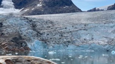 Grönland Kutup Bölgesi 'nin nefes kesici güzelliğini tecrübe edin. Devasa buzulların ve yükselen buzdağlarının el değmemiş turkuaz sularda zarafetle yüzdüğü yer. Bu sakin ama dramatik sahne ham gücü vurguluyor.