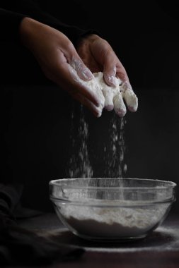 Ekin manzaralı kadın elleri süzgeçten un geçiriyor.