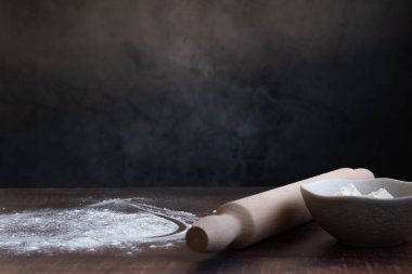 Fırın malzemeleri arka planda - koyu arka planda un ve merdane, sağlıklı temel pişirme malzemeleri. Metin için boşluk