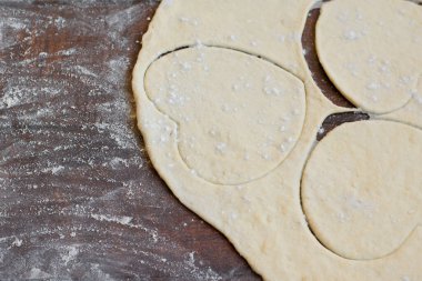 Fırın malzemeleri - ahşap unlu arka planda kalbe yerleştirilmiş hamur mayası.