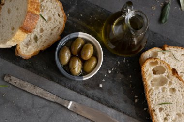 İtalyan dilimlenmiş ciabatta ekmeği otlarla doğranmış, ekstra bakire yağı ve koyu grunge arka planda marine edilmiş zeytinler.