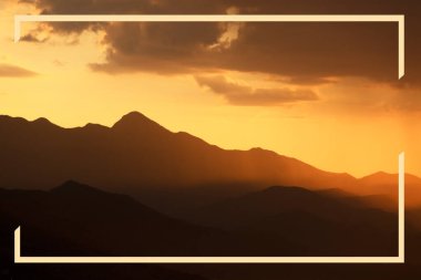 Dağlar gün batımında gökyüzünde şekillenir. Renkli günbatımına sahip rahatlatıcı dağ manzarası, doğa gezisi arka planı.