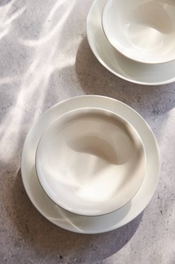 Boş beyaz kaseler betonun üzerinde, güneşli bir masanın üzerinde.