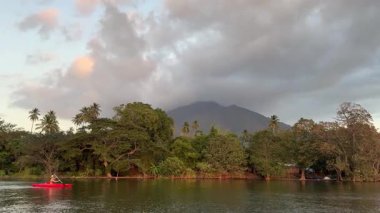 Olgun bir kadın, Nikaragua Gölü 'nün dingin güzelliğinin ve görkemli Concepcion volkanının tadını çıkararak Ometepe Adası yakınlarında kayak yapıyor..