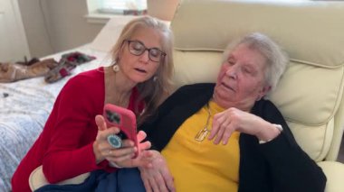 Bir ev sağlık merkezinde sıcak bir anda yaşlı bir asistanla yakınlaşıyor, telefonda gülücükler ve hikayeler anlatıyor.