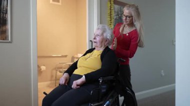 Bakıcı, kaldığı süre boyunca konfor ve refakatin sağlanması için, bir ev sağlık merkezinde yaşlı bir kadına destek veriyor..