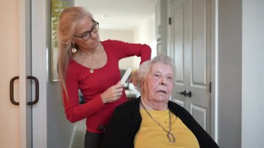 Bakıcı yaşlı bir kadının saçını nazikçe tarar. Bir sağlık merkezinde, günlük bakım ve nafaka göstererek..