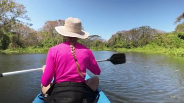 Olgun bir kadın, Orta Amerika 'daki Nikaragua' daki Ometepe Adası 'nda bereketli doğayla çevrili, huzurlu Riolstian bataklığında kano ile gezer..