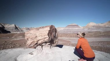Olgun bir kadın, eşsiz kaya oluşumlarına ve açık araziye hayran olduğu için Blue Mesa, Petrified Forest Ulusal Parkı, Arizona 'da yürüyüş yapıyor..