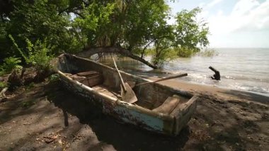 Nikaragua 'daki Ometepe Adası' nın kıyısında bir ahşap kayık dinlenirken, orman suların kenarındaki bölgeyi çevrelemektedir..