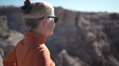 Olgun bir kadın Arizona 'daki Petrified Forest Ulusal Parkı' ndaki Mavi Mesa bölgesini keşfederken açık havanın ve çarpıcı manzaranın tadını çıkarıyor.