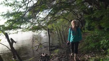 Olgun bir kadın, Ometepe Adası 'ndaki Charco Verde parkında, suların kenarında yürüyor, bereketli ormanı ve doğa patikalarını keşfediyor..