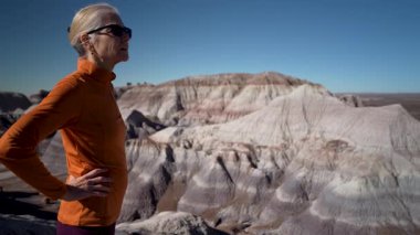 Olgun bir kadın Arizona 'daki Petrified Forest Ulusal Parkı' nda Mavi Mesa 'da yürüyüş yaparken çevresindeki manzaranın tadını çıkarıyor..