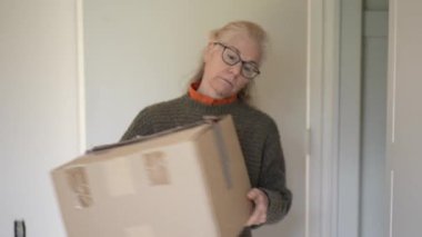 Olgun kadın oturma odasında aile antikaları ve aile yadigârlarıyla dolu kutuları açıp mirasını ve anılarını keşfediyor..