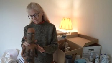 Olgun bir kadın, aile hazineleriyle dolu bir kutuyu açar ve aile yadigârları ile ilgili anılarını ve yurtdışına seyahat eden antikalarını paylaşır..