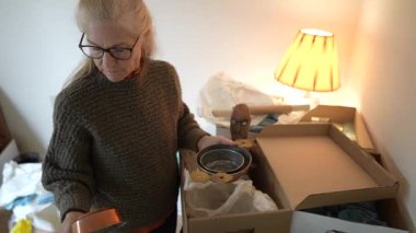 Olgun bir kadın, aile yadigârlarını ve aile yadigarlarını açmak için bir kutu açar. Sıcak bir odada yumuşak ışıkla anılarını paylaşır..