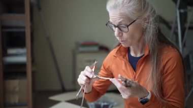 Olgun kadın kalıtsal gümüş çatal bıçak takımlarına bakar, aile anılarını ve aile yadigarlarının mirasını yansıtır..