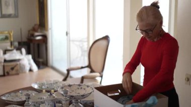 Olgun kadın, aile yemeklerinden ve geçmişiyle olan bağlantılarını hatırlayarak miras kalan porselen yemek takımlarını açıyor..