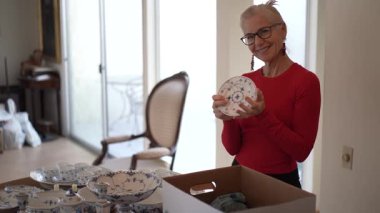 Olgun kadın antika porselenleri açıyor ve evindeki özel yemeklerde sıcak aile anılarını hatırlıyor..