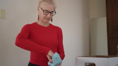 Olgun kadın miras kalan porselenleri açıyor ve yemek odasını sevgi ve sıcaklıkla dolduran aile toplantılarının anılarını paylaşıyor..